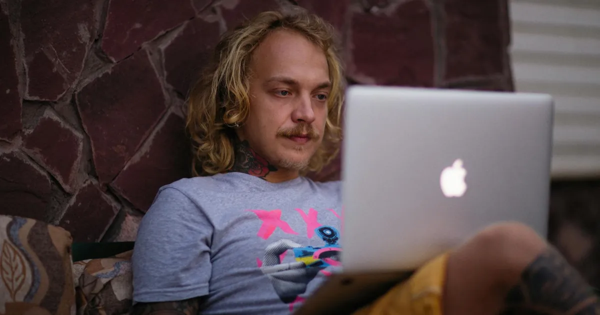 Caucasian man working remotely outdoors using a laptop, embodying the digital nomad lifestyle.