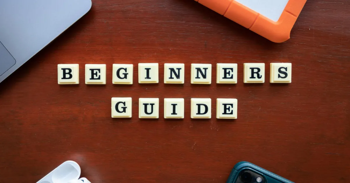 Creative flat lay of gadgets and 'Beginners Guide' text on wooden table.