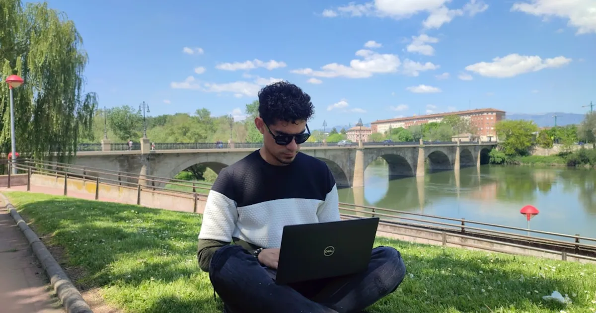 a man sitting on grass with a laptop