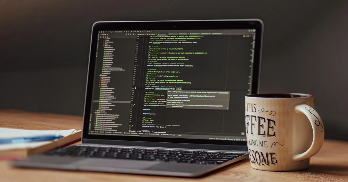 Laptop displaying code editor with coffee mug on desk, perfect for tech themes.