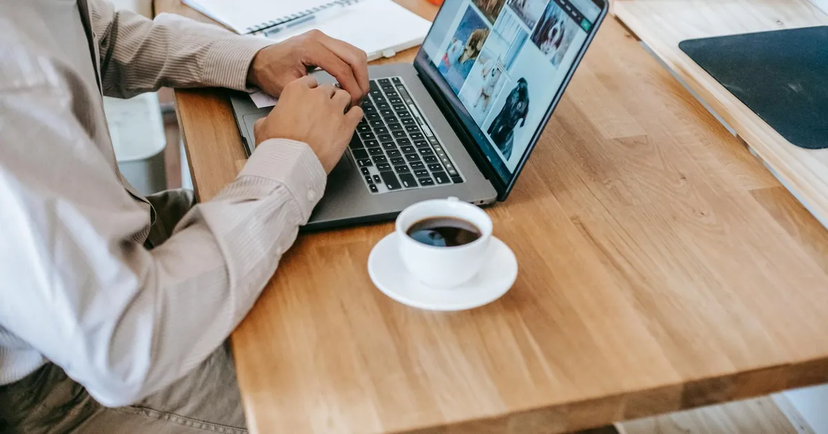A person working on a laptop while enjoying a coffee at home, depicting a casual and productive workspace.