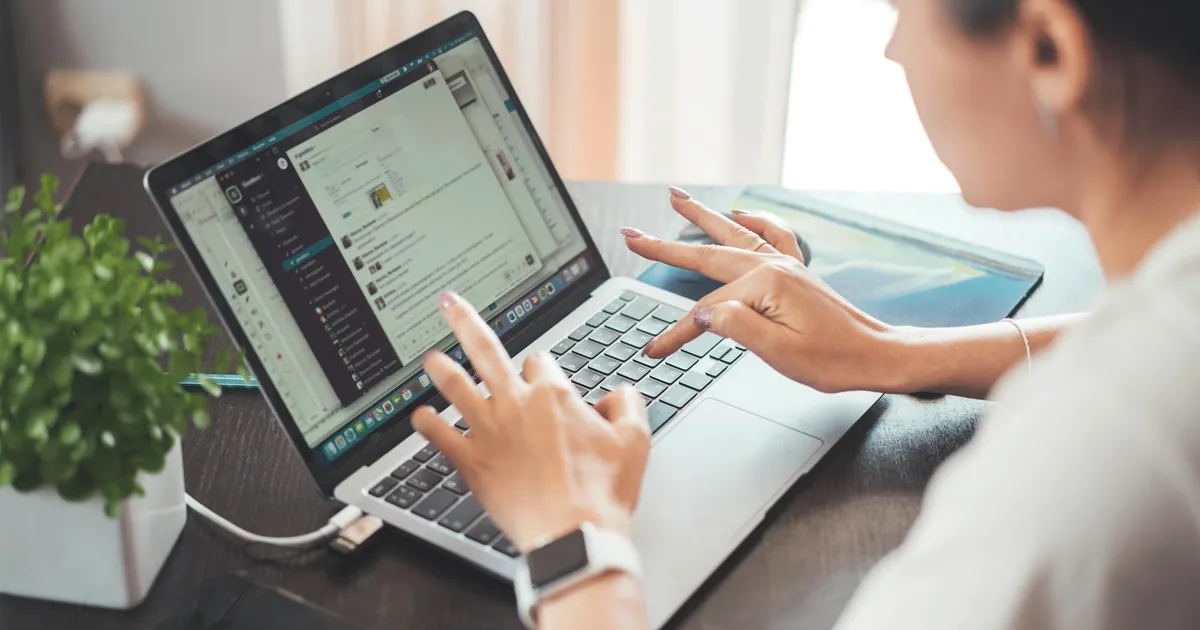 A woman working on a laptop from home, focusing on digital tasks and communication.
