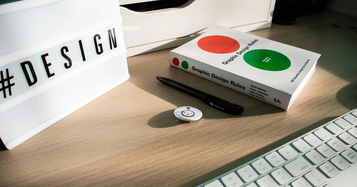 A modern desk setup featuring design elements like a book, #DESIGN sign, and accessories.