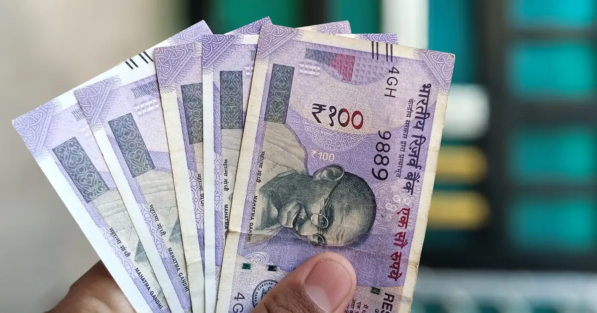 Close-up view of holding Indian 100 rupee banknotes, showcasing currency details and design.