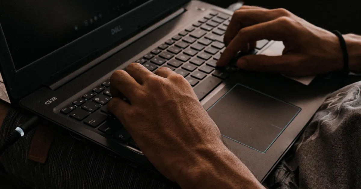 Focused close-up of hands typing on a laptop keyboard, showcasing digital work and technology.