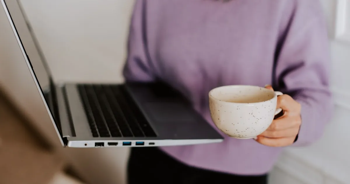 a woman holding a coffee cup and a laptop
