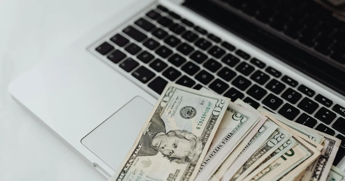 Close-up of US dollar banknotes on a laptop keyboard symbolizing online finance and technology.