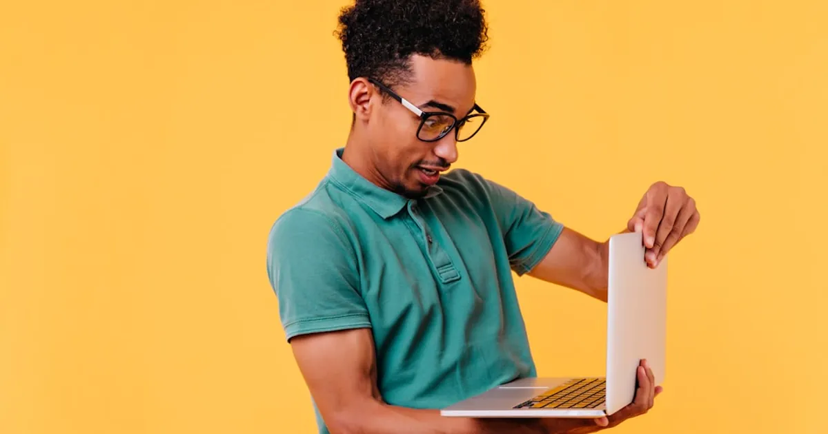 a man in a green shirt holding a laptop