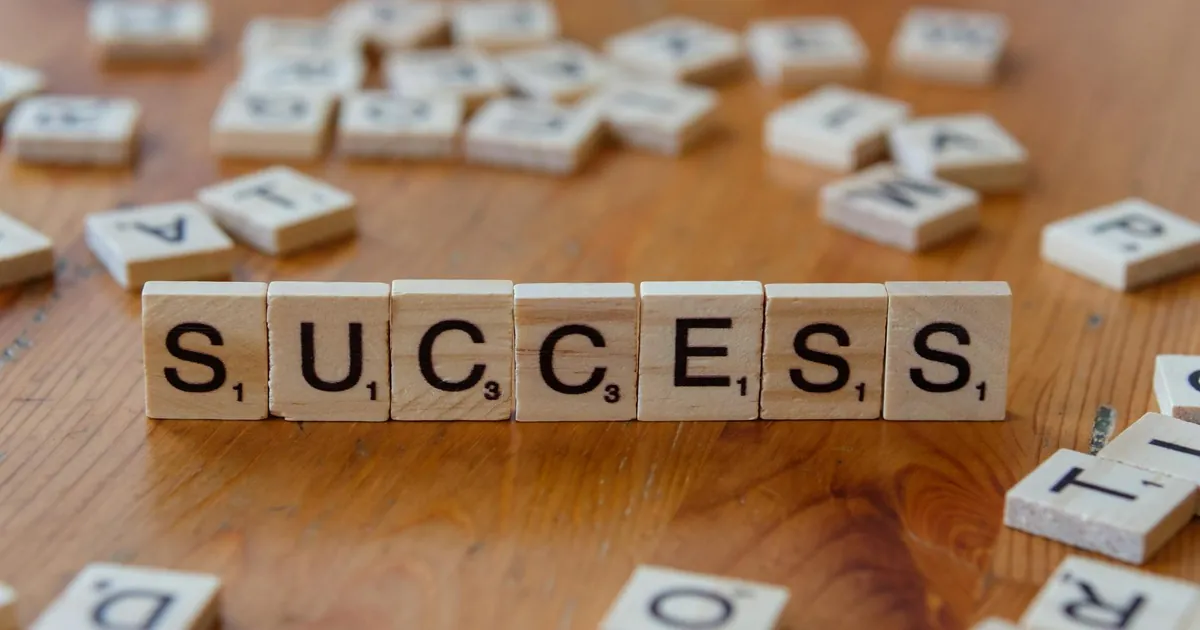 Wooden letter tiles spelling 'success' on a scattered background, symbolizing achievement.