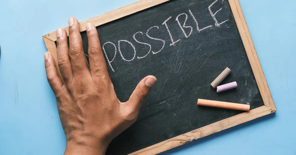 A hand on a chalkboard with 'Possible' written in chalk signifies optimism and potential.
