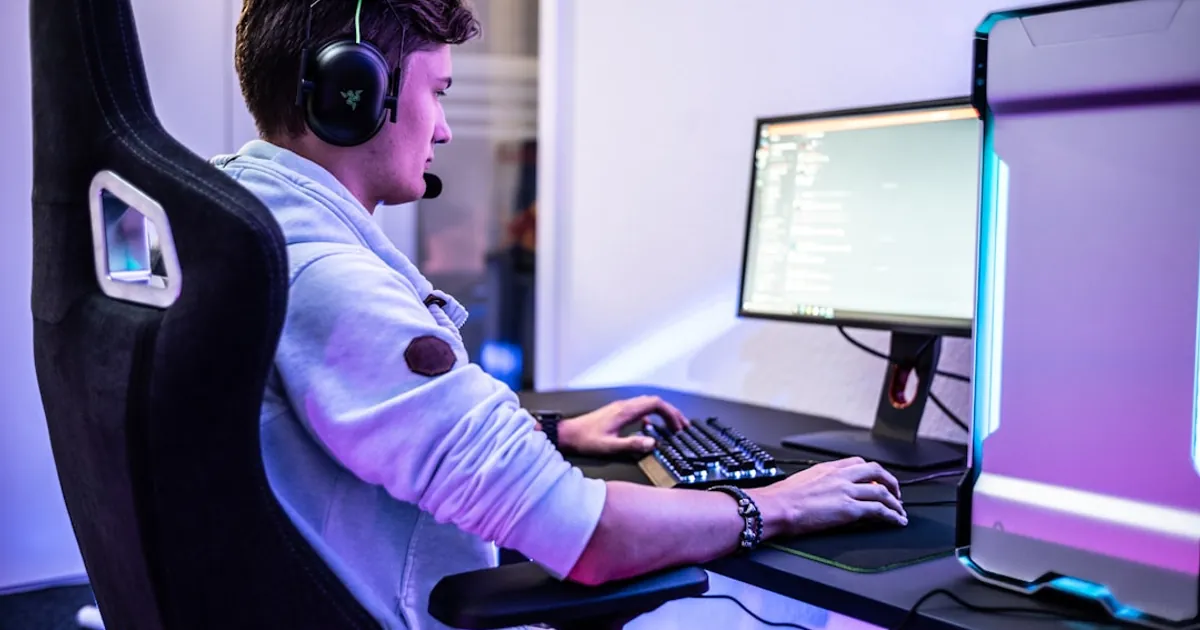 a young man wearing headphones sitting in front of a computer
